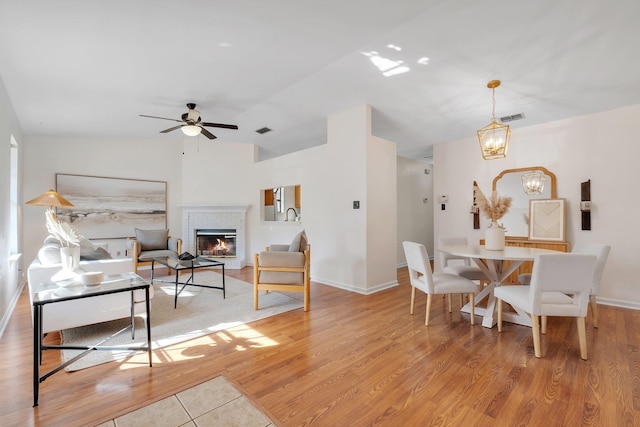 living room with ceiling fan with notable chandelier and light wood-type flooring