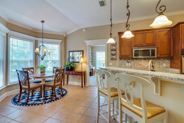 2605 Antietam Trl, Tallahassee, FL 32312 - kitchen with stainless steel microwave, healthy amount of natural light, brown cabinets, light tile patterned flooring, and ornamental molding
