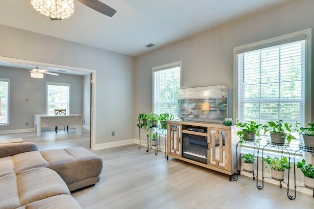 2605 Antietam Trl, Tallahassee, FL 32312 - living room with light wood-style floors, baseboards, a ceiling fan, a chandelier, and a glass covered fireplace
