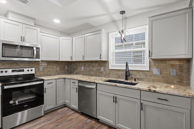 kitchen featuring a sink, decorative light fixtures, backsplash, dark wood finished floors, and stainless steel appliances