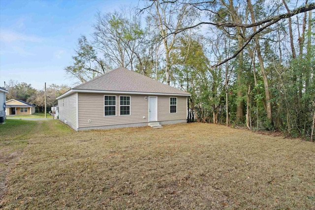 rear view of property featuring a yard and roof with shingles