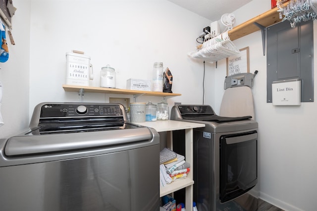 laundry room with electric panel, washer and dryer, and hardwood / wood-style flooring