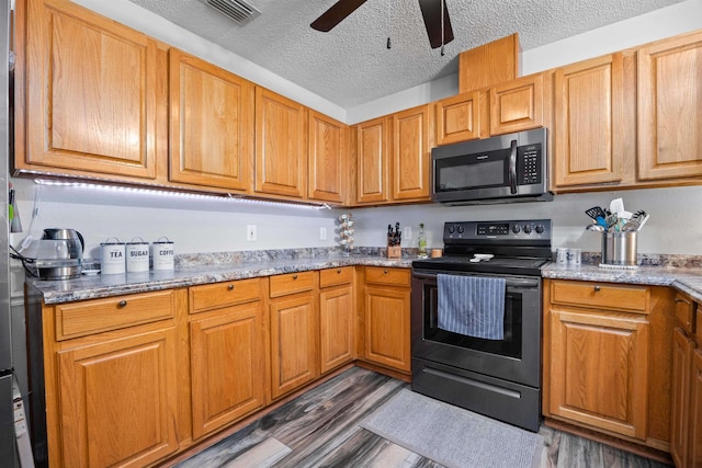 kitchen with ceiling fan, a textured ceiling, light stone counters, dark hardwood / wood-style flooring, and stainless steel appliances