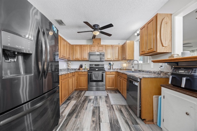 kitchen featuring visible vents, appliances with stainless steel finishes, wood finished floors, a ceiling fan, and a sink