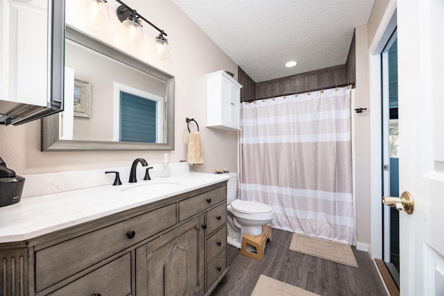 bathroom with vanity, hardwood / wood-style flooring, toilet, a textured ceiling, and curtained shower