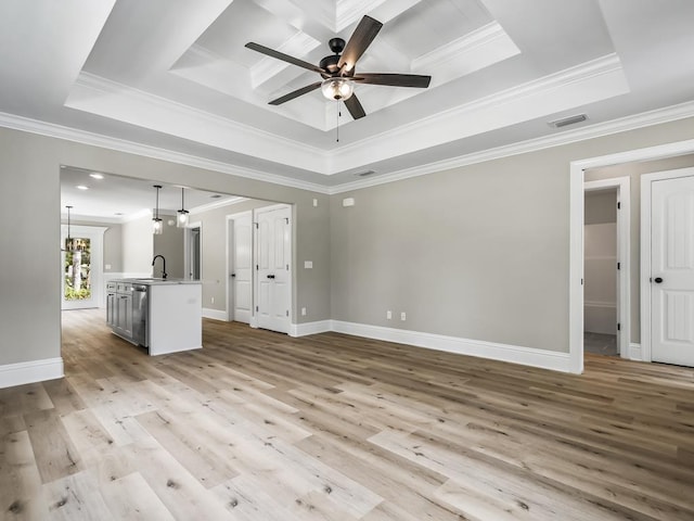 unfurnished living room featuring a tray ceiling, sink, and ornamental molding