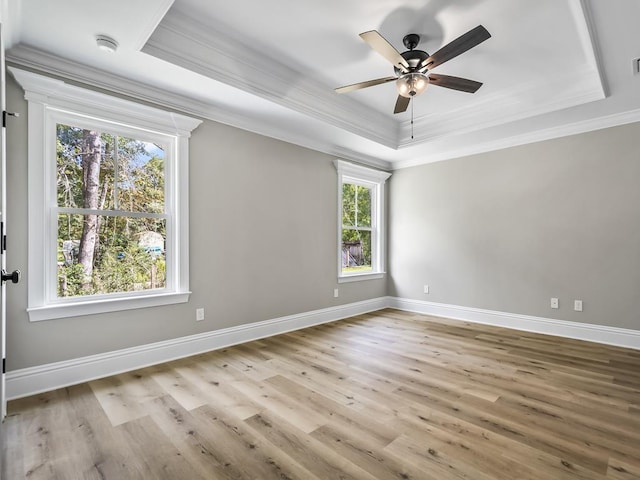 spare room featuring a tray ceiling, crown molding, ceiling fan, and light hardwood / wood-style floors