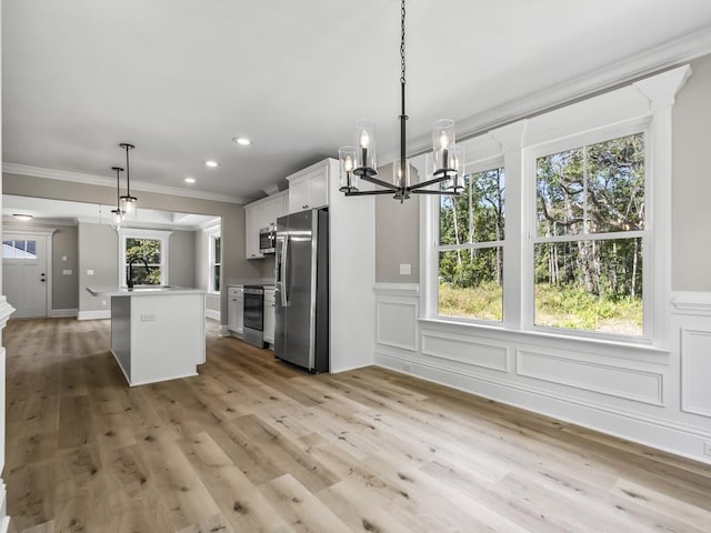 kitchen with appliances with stainless steel finishes, a healthy amount of sunlight, white cabinets, a center island, and hanging light fixtures