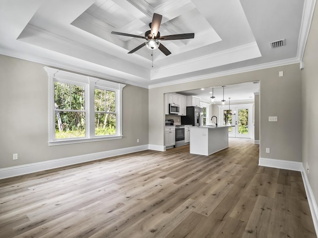 unfurnished living room with a tray ceiling, crown molding, and wood-type flooring