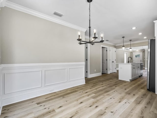 unfurnished dining area with a chandelier, light hardwood / wood-style floors, crown molding, and sink