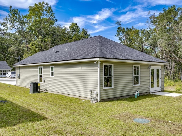 view of property exterior with french doors, a yard, and central AC unit