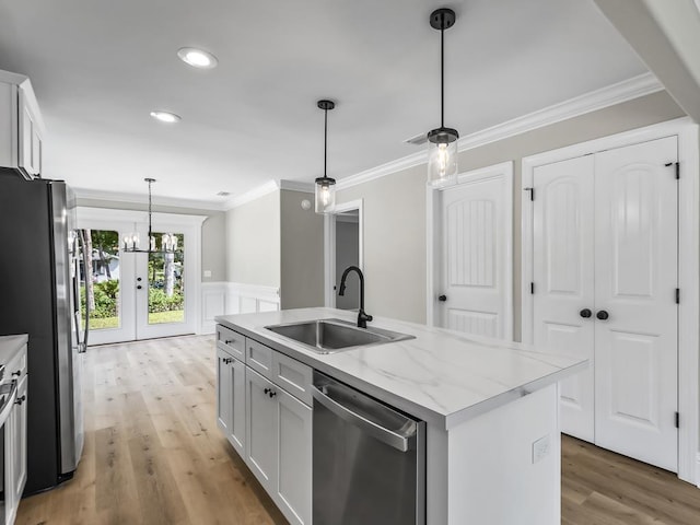 kitchen with white cabinets, sink, an island with sink, appliances with stainless steel finishes, and light stone counters