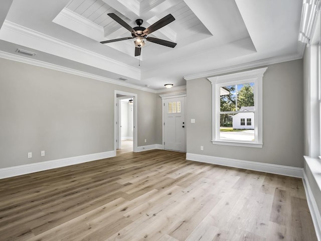 empty room featuring a tray ceiling, ceiling fan, ornamental molding, and light wood-type flooring