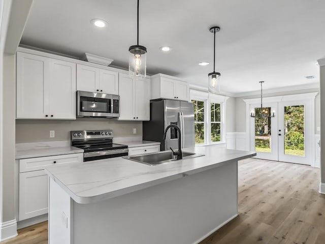 kitchen with a center island with sink, decorative light fixtures, sink, and appliances with stainless steel finishes