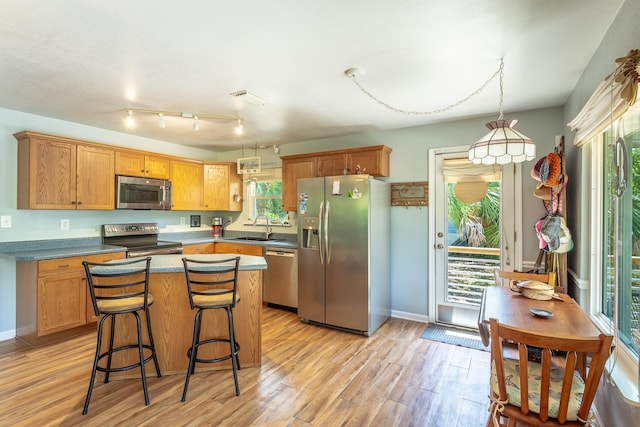 627 Mariner Cir, Alligator Point, FL 32346 - kitchen with appliances with stainless steel finishes, light wood-style floors, a sink, a center island, and a breakfast bar