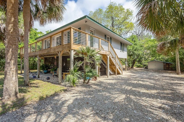 627 Mariner Cir, Alligator Point, FL 32346 - view of front of house with stairway, an outdoor structure, a deck, and gravel driveway