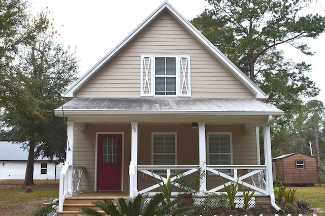 bungalow featuring a porch and a storage unit