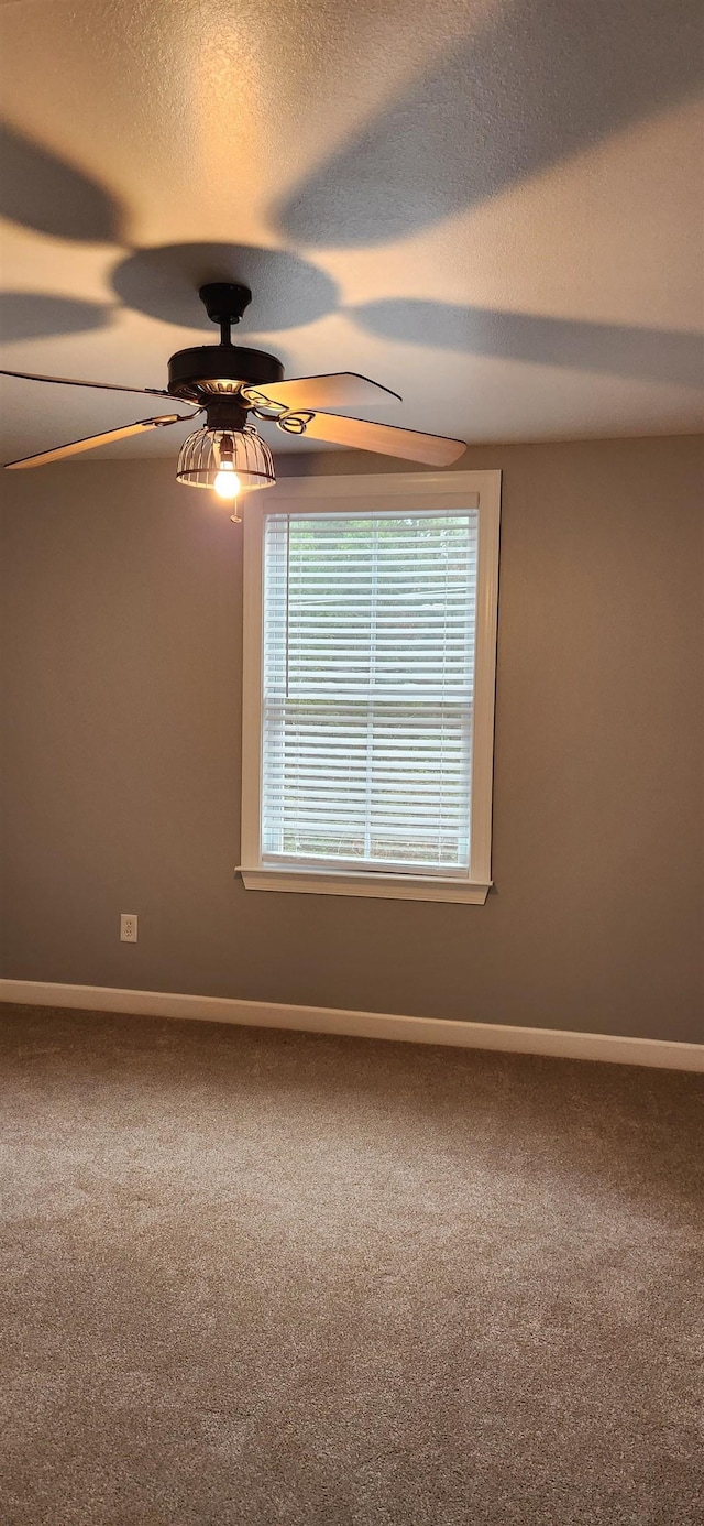 carpeted spare room featuring ceiling fan