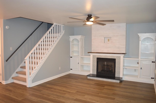 unfurnished living room with a fireplace, dark hardwood / wood-style floors, and ceiling fan