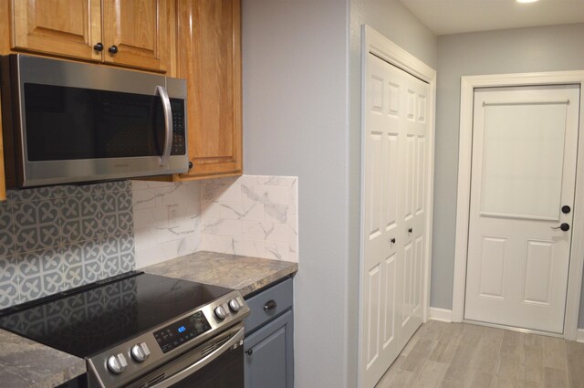 kitchen featuring light wood-type flooring, stainless steel appliances, and tasteful backsplash