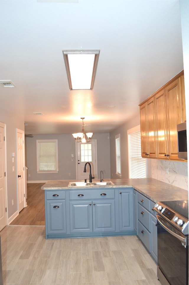 kitchen with backsplash, stainless steel appliances, sink, an inviting chandelier, and light hardwood / wood-style floors