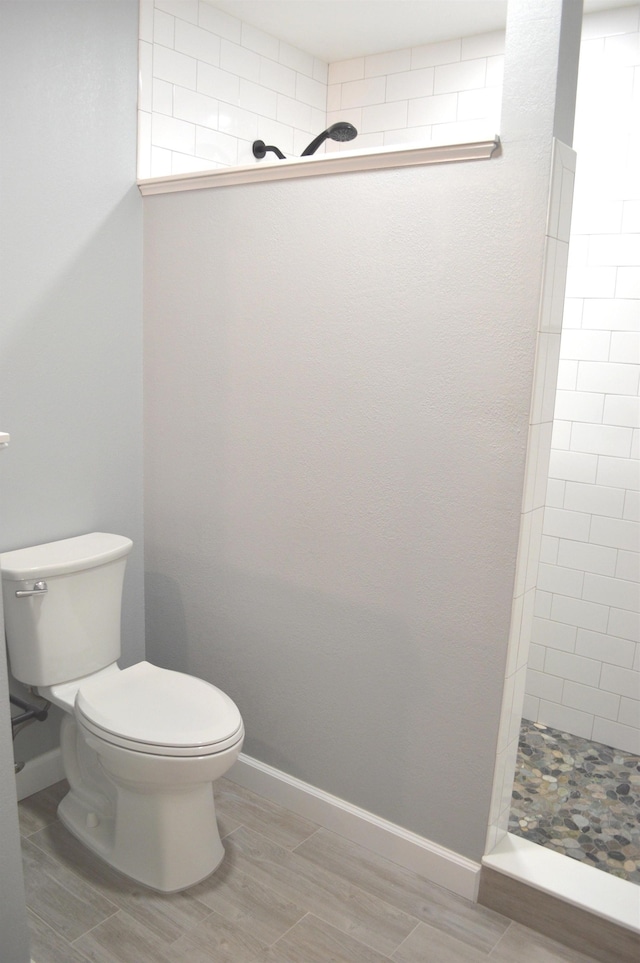 bathroom featuring toilet and a tile shower