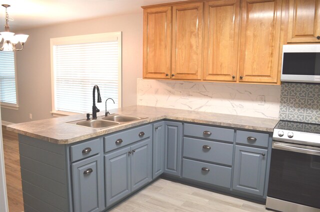 kitchen with gray cabinetry, backsplash, an inviting chandelier, sink, and range