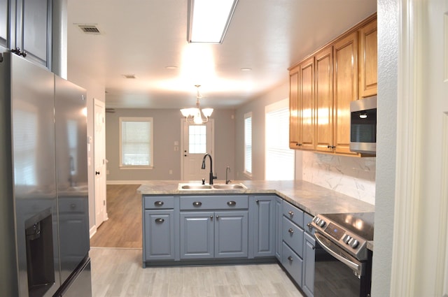 kitchen with backsplash, gray cabinetry, light wood-type flooring, and appliances with stainless steel finishes