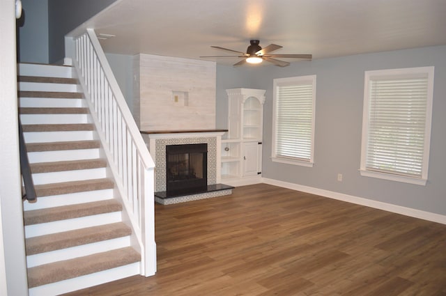 unfurnished living room with ceiling fan, dark hardwood / wood-style flooring, and a tile fireplace