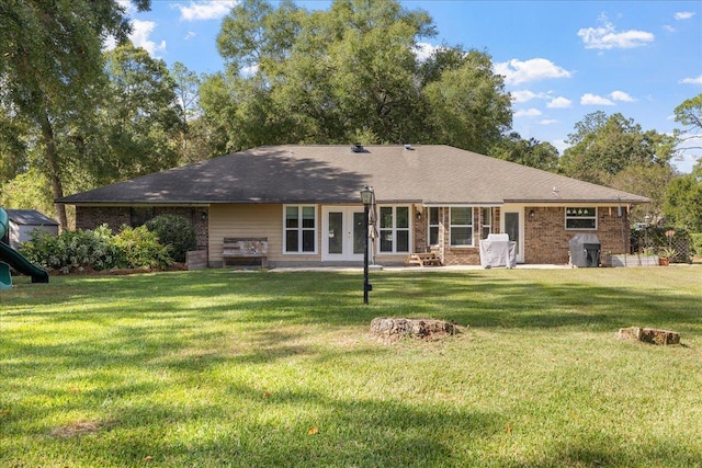 back of property featuring a patio area, a playground, a lawn, and brick siding