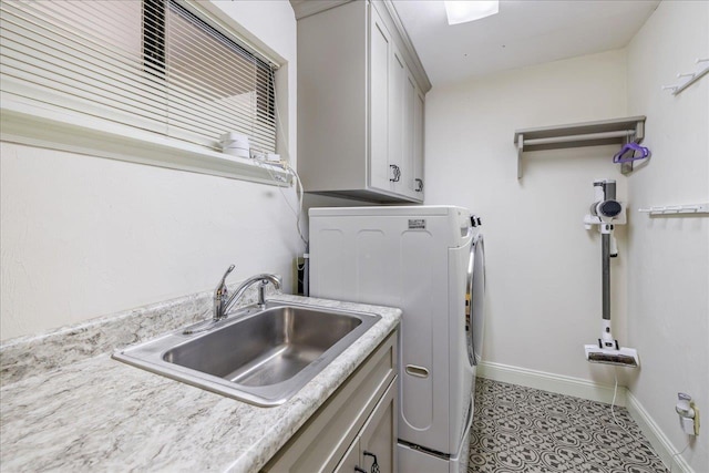 washroom with light tile patterned floors, cabinet space, washing machine and dryer, a sink, and baseboards