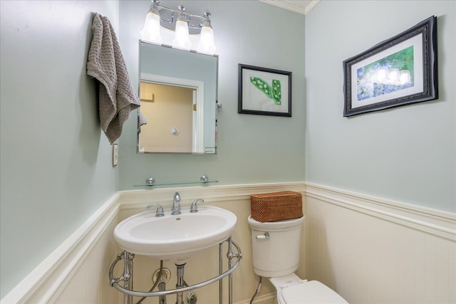 bathroom with a wainscoted wall, a sink, and toilet