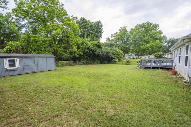 3204 Gallant Fox Trl, Tallahassee, FL 32309 - view of grassy yard featuring a deck, an outbuilding, view of scattered trees, and a storage shed