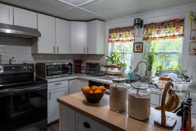 kitchen with white cabinets, decorative backsplash, stainless steel appliances, and ornamental molding