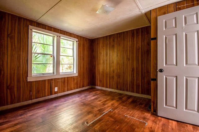 unfurnished room featuring wooden walls and dark wood-type flooring