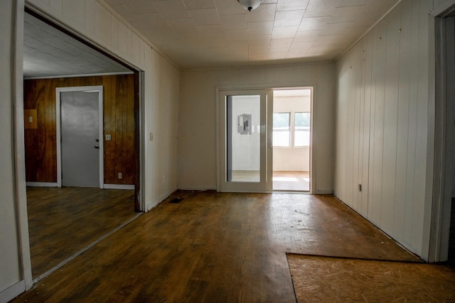 foyer entrance featuring dark hardwood / wood-style flooring, ornamental molding, and wood walls