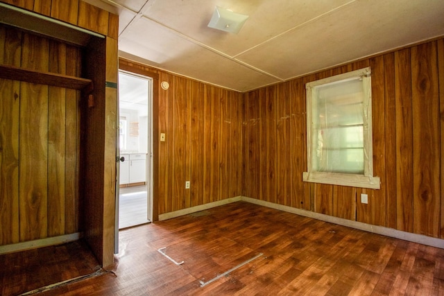 unfurnished room featuring wood walls and dark hardwood / wood-style flooring