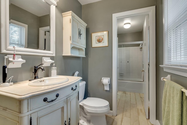 full bathroom featuring hardwood / wood-style flooring, vanity, bath / shower combo with glass door, and toilet