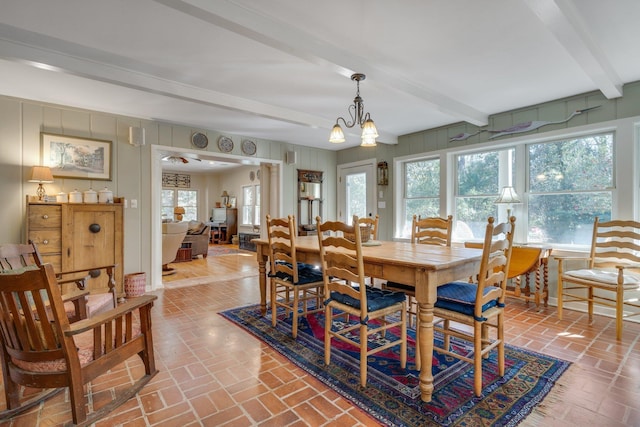 dining area featuring beamed ceiling and an inviting chandelier