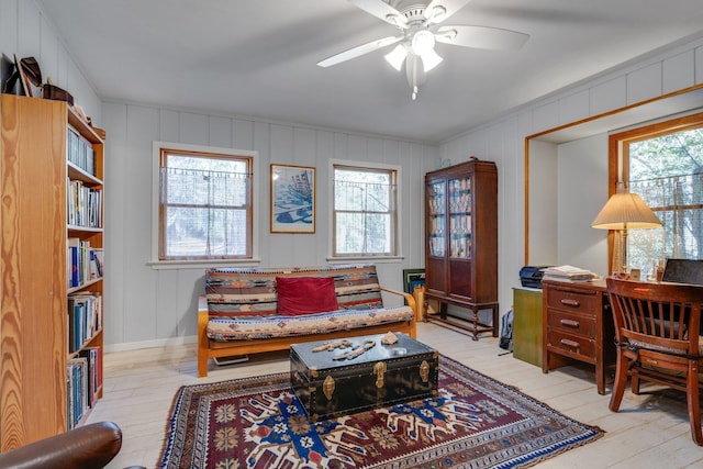 living area with ceiling fan, a wealth of natural light, and light hardwood / wood-style floors