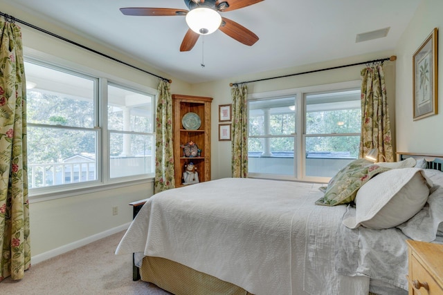 bedroom featuring ceiling fan, light colored carpet, and multiple windows