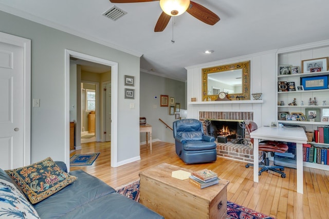 living room featuring hardwood / wood-style flooring, ornamental molding, ceiling fan, and a fireplace