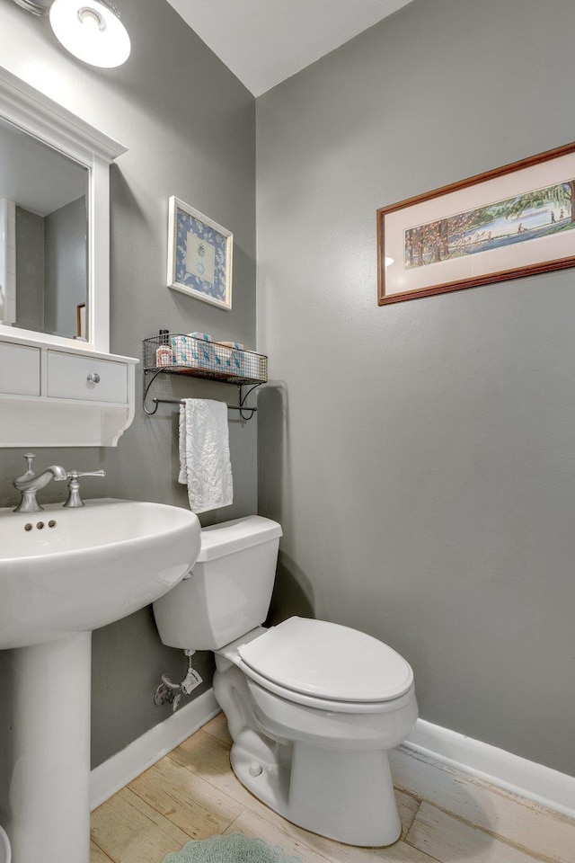 bathroom with wood-type flooring, toilet, and sink