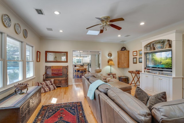 living room with a skylight, crown molding, light hardwood / wood-style flooring, and ceiling fan