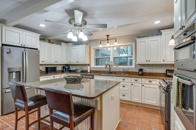 kitchen featuring sink, a breakfast bar area, appliances with stainless steel finishes, a center island, and white cabinets