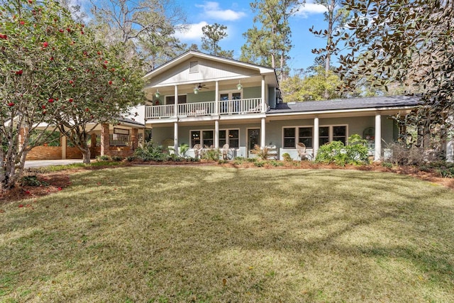 rear view of house with a balcony, covered porch, ceiling fan, and a lawn