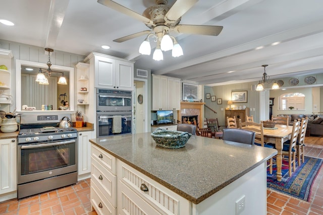 kitchen featuring white cabinetry, a center island, hanging light fixtures, appliances with stainless steel finishes, and beam ceiling