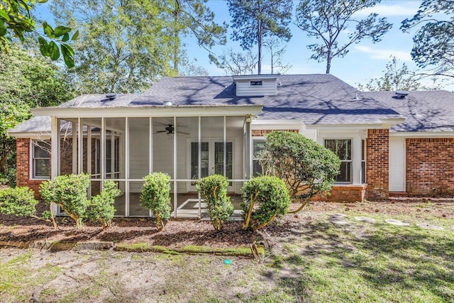 rear view of property with a shingled roof, a sunroom, and brick siding