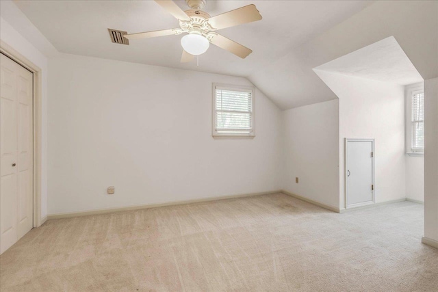 bonus room featuring lofted ceiling, light colored carpet, a ceiling fan, baseboards, and visible vents