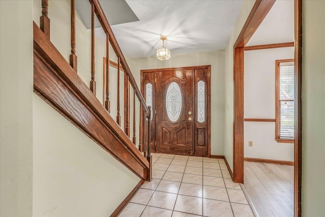 entryway featuring light tile patterned floors, baseboards, and stairs